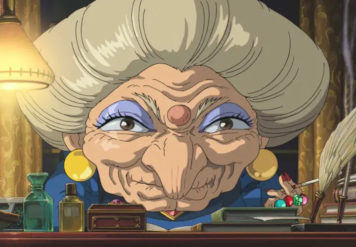 La strega Yubaba, figura chiave de "La città incantata", con il suo sguardo penetrante e la sua scrivania piena di oggetti misteriosi.