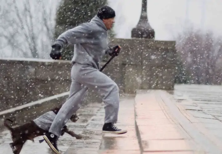 Rocky Balboa, dopo un duro incontro, si allena sotto la neve con il suo cane.