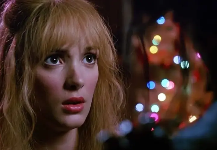 Kim, con sguardo preoccupato, è illuminata da luci colorate, un momento intenso con Edward mani di forbice.