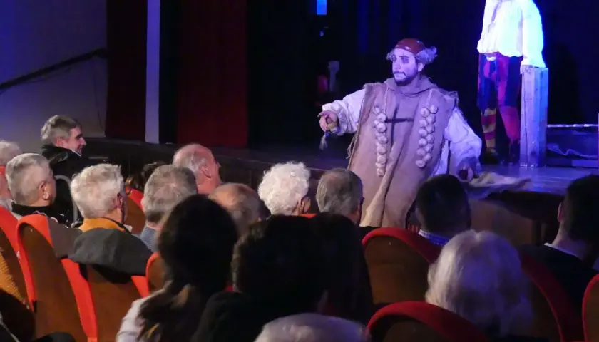 Attori in costume sul palco, il pubblico osserva la rappresentazione teatrale, infrangendo la **quarta parete teatro**.