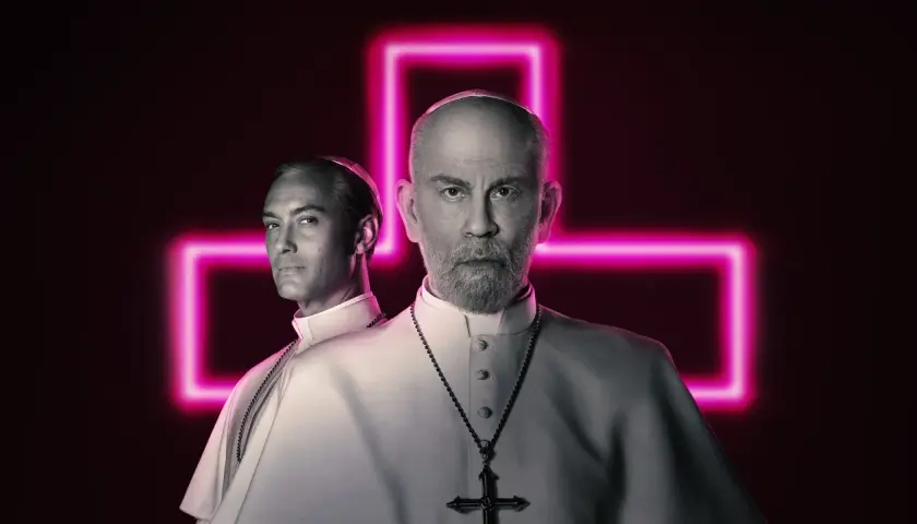 Due papi, uno giovane e uno anziano, sullo sfondo di una croce al neon rosa. La recensione del nuovo papa è intensa.