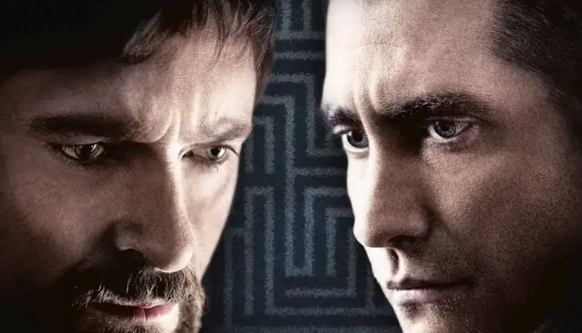 Primo piano dei volti intensi del cast di Prisoners, Hugh Jackman e Jake Gyllenhaal, con uno sfondo a labirinto.