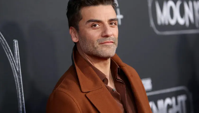 Oscar Isaac, l'attore di Moon Knight, posa con un cappotto marrone.