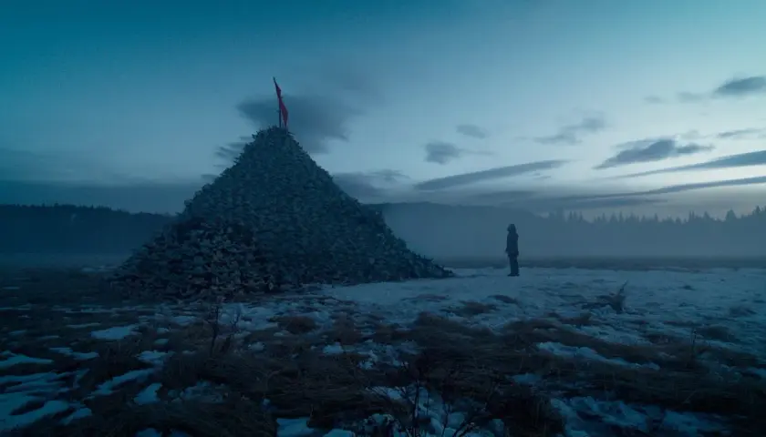Un uomo solitario osserva un'enorme piramide di teschi in un paesaggio innevato. Un'immagine che evoca le recensioni de "The Revenant".