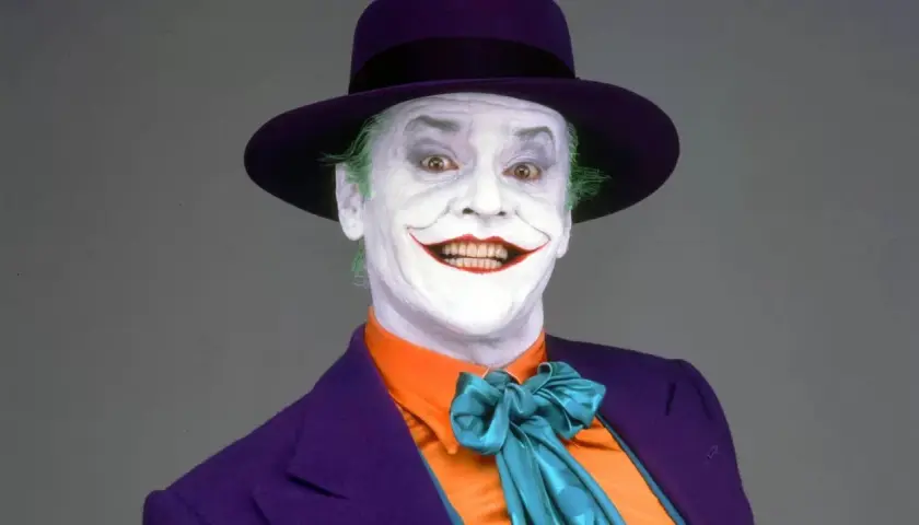 Jack Nicholson nel suo iconico ruolo di Joker, primo film, con trucco bianco, capelli verdi e cappello viola.