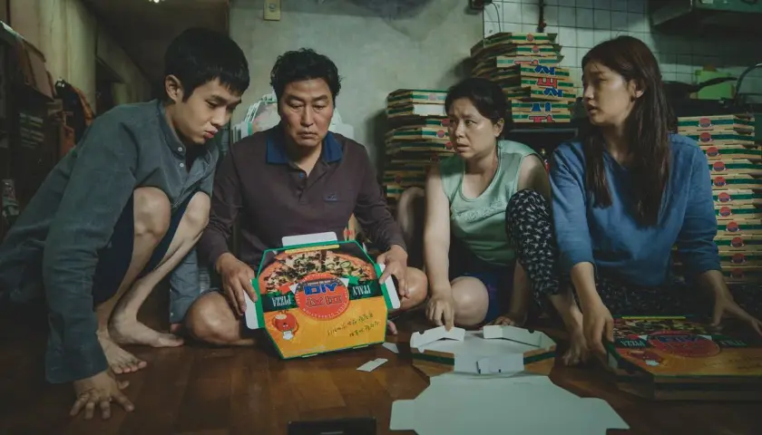 La famiglia Kim assembla scatole per pizza, una scena chiave nella **recensione** di "Parasite".