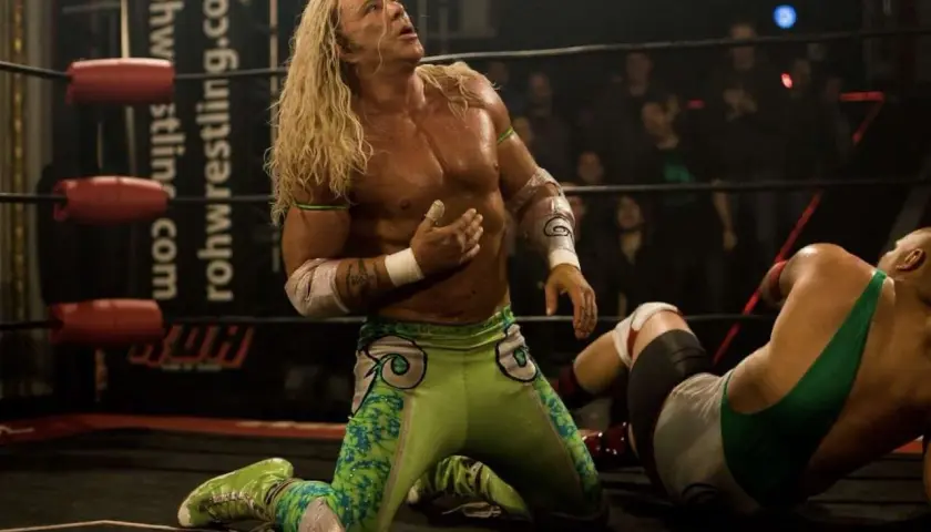 Randy the Ram, il wrestler dai lunghi capelli biondi, in ginocchio sul ring, guarda verso l'alto con espressione intensa.