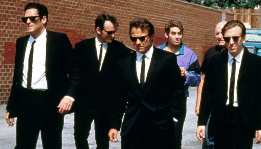 Sei uomini in abito nero camminano in gruppo, un cast cinematografico iconico.