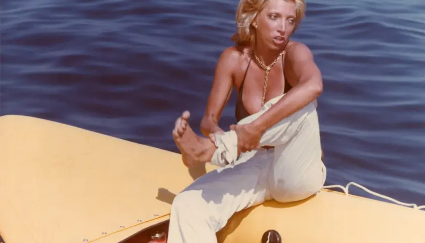 Donna bionda su un gommone giallo, travolta da un insolito destino curiosità, con il mare blu sullo sfondo.