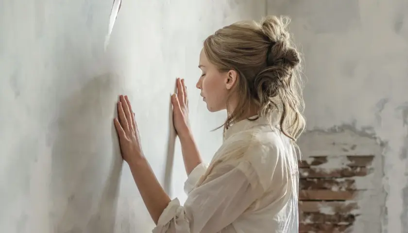 Donna con le mani sul muro, forse in attesa di una notizia o in un momento di riflessione. Una madre in attesa, la sua recensione interiore.