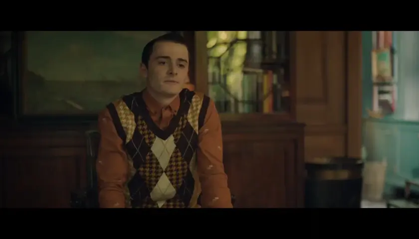 Il cast di The Tutor in un'ambientazione classica. Un giovane con un gilet a rombi su una camicia arancione.
