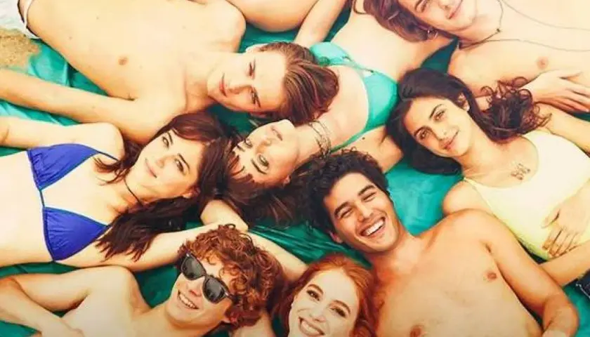 Giovani sorridenti sdraiati al sole, un'immagine che evoca le vacanze estive e le recensioni positive di "Sotto il sole di Riccione".