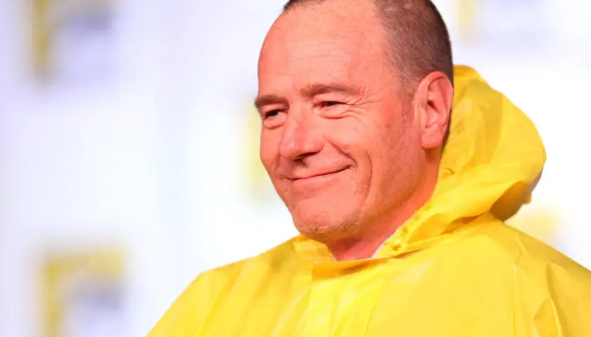 Bryan Cranston sorride con la sua iconica tuta gialla, ricordando le citazioni di Breaking Bad.
