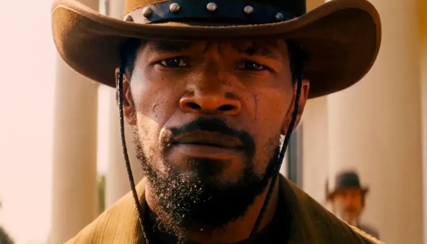 Primo piano di Django, con cappello da cowboy e barba. Il suo sguardo intenso evoca il significato di libertà e vendetta in Django Unchained.