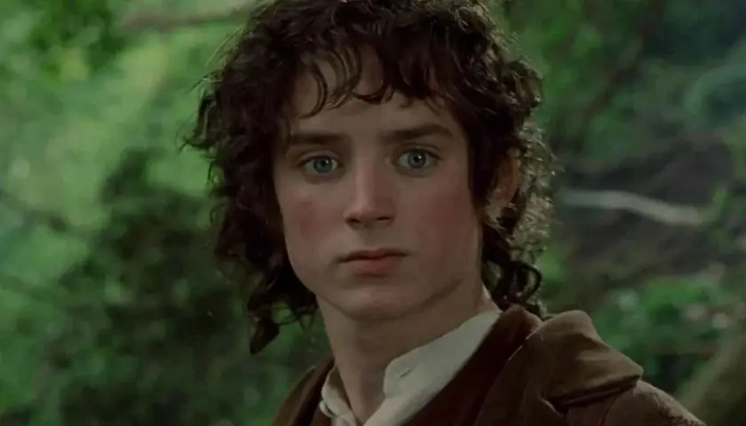 Primo piano di Elijah Wood nei film de Il Signore degli Anelli, con occhi azzurri penetranti e capelli castani mossi.