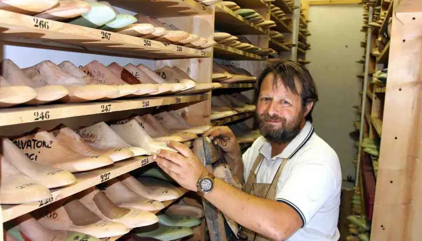 Un calzolaio sorridente in bottega, circondato da forme di legno per scarpe. Sembra Daniel Day Lewis, immerso nel suo mestiere.