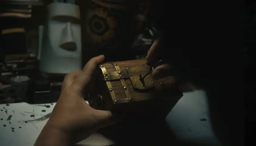 Mani che aprono un forziere, forse il tesoro di Gold Roger di One Piece. Sullo sfondo, una statua Moai e oggetti misteriosi.