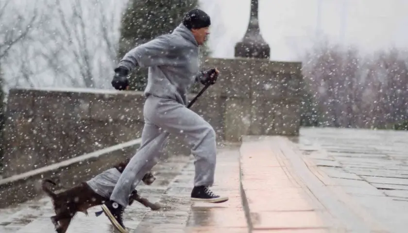 Rocky Balboa, dopo un duro incontro, si allena sotto la neve con il suo cane.