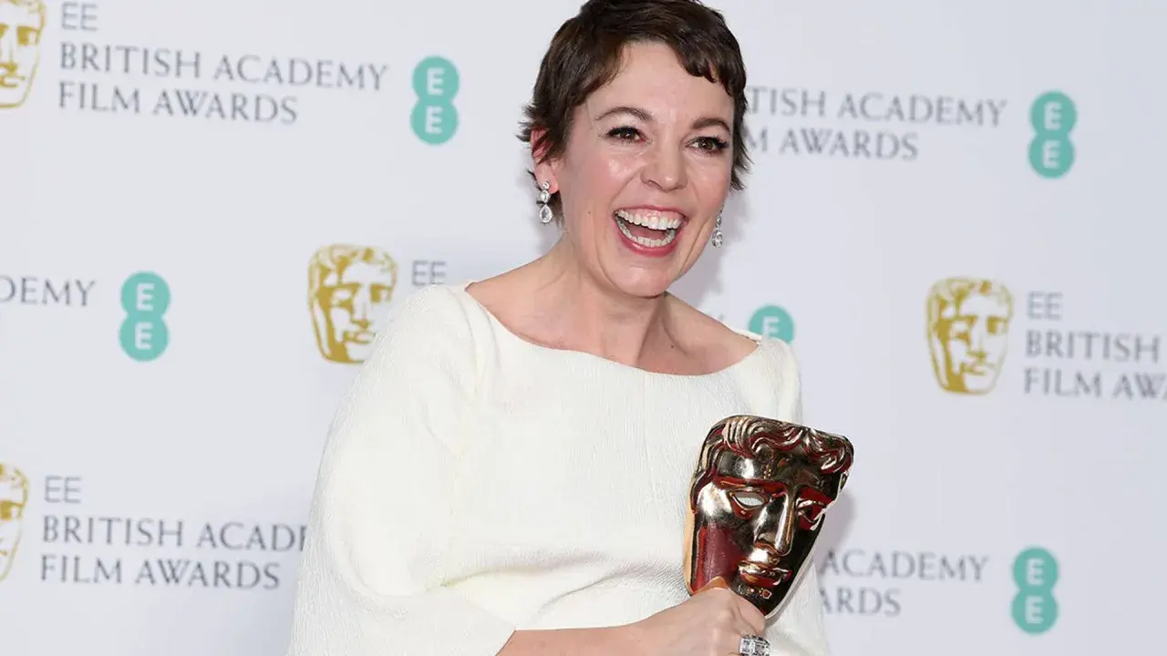 Olivia Colman, raggiante, celebra i suoi premi vinti da attrice, stringendo un BAFTA dorato.