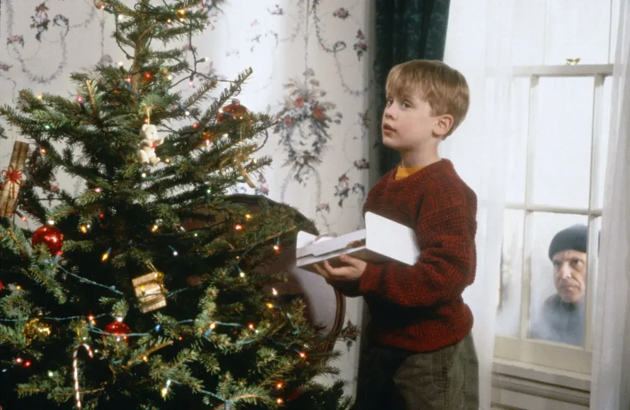 Kevin, protagonista di "Mamma, ho perso l'aereo", guarda sorpreso un intruso fuori dalla finestra, vicino all'albero di Natale.