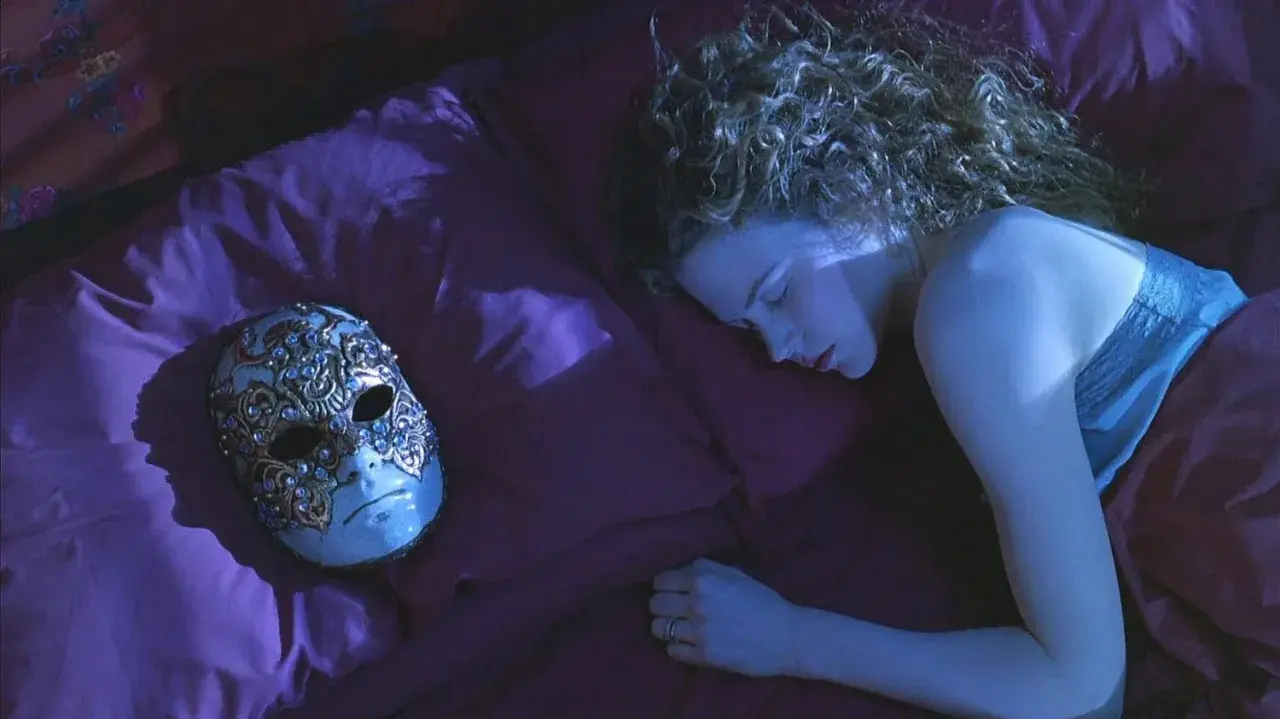 Una donna dorme su un letto di seta viola, accanto a una maschera veneziana ornata. La sua curiosità è palpabile, come se stesse sognando occhi chiusi.