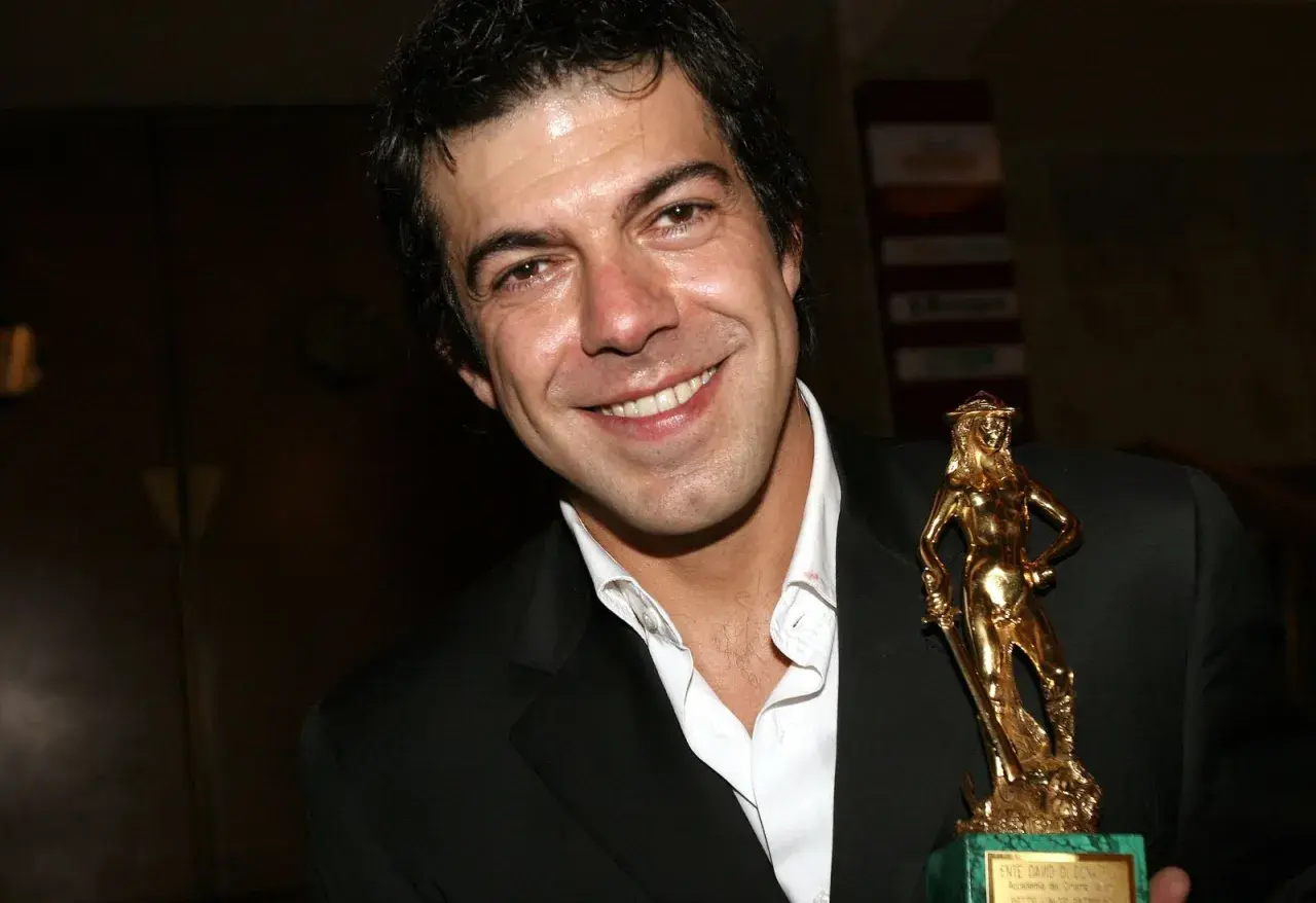Favino giovane sorride con un premio David di Donatello dorato.