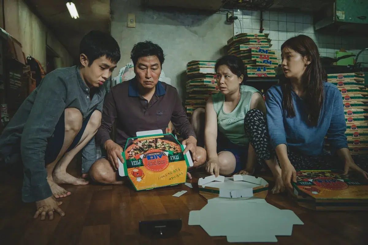La famiglia Kim assembla scatole per pizza, una scena chiave nella **recensione** di "Parasite".