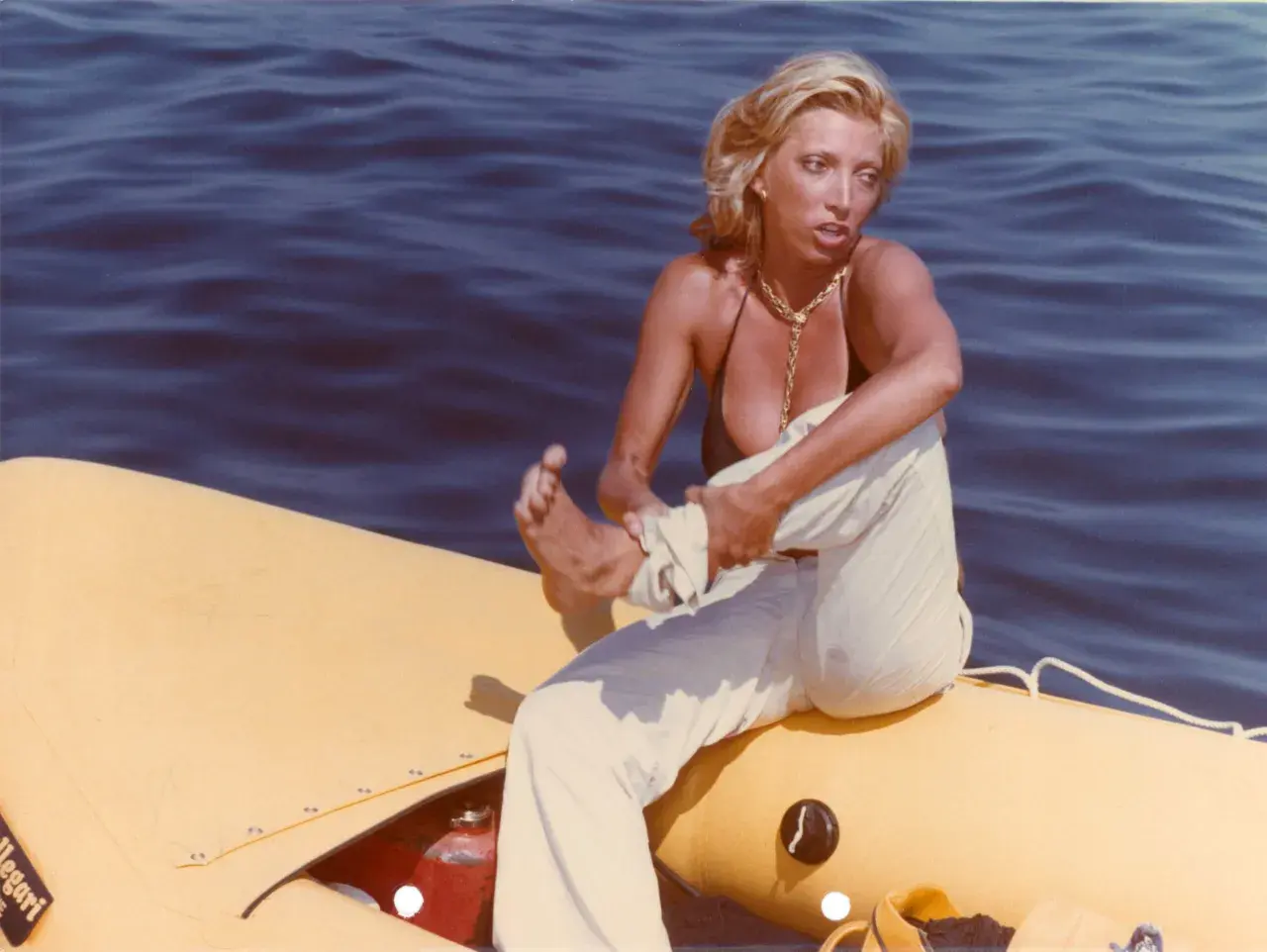 Donna bionda su un gommone giallo, travolta da un insolito destino curiosità, con il mare blu sullo sfondo.