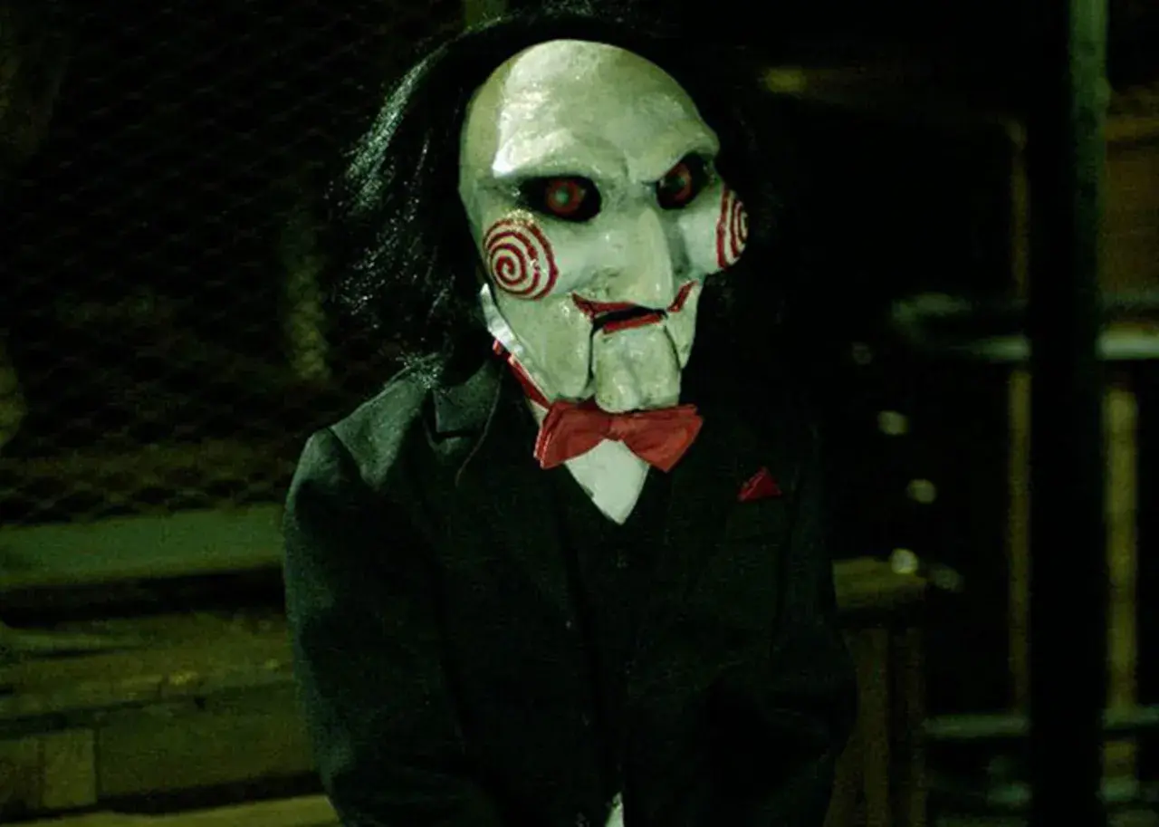 La maschera di Billy, il pupazzo di **jigsaw saw**, con i suoi vortici rossi e occhi rossi, indossa un abito elegante.