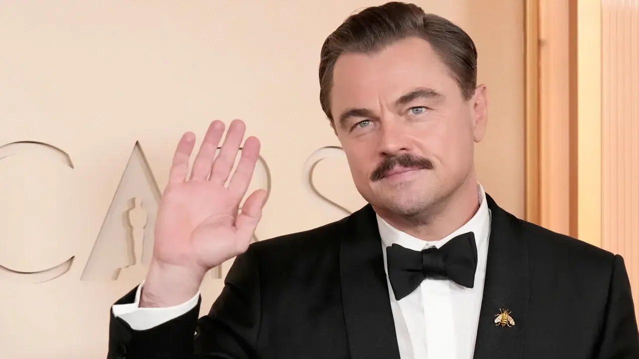 Leonardo DiCaprio, con baffi e smoking, saluta. Quanti Oscar ha vinto Leonardo DiCaprio? Uno, per "The Revenant".