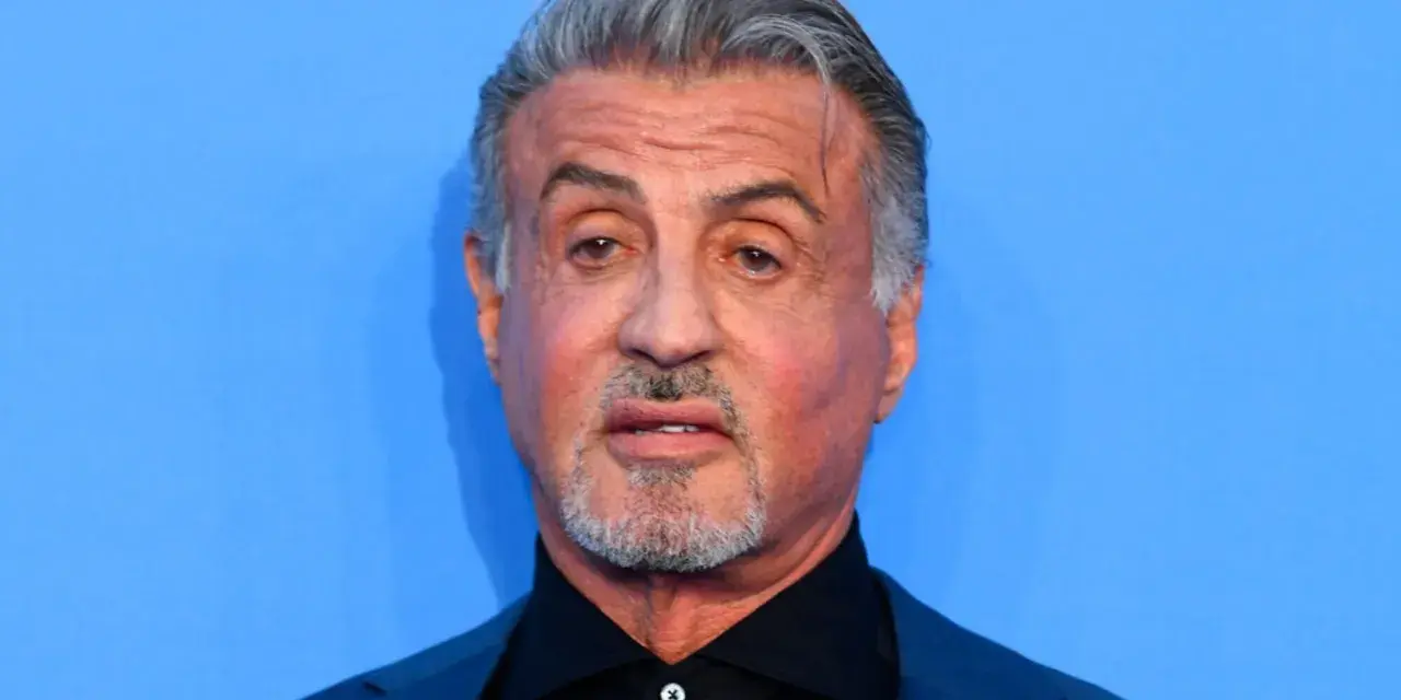 Sylvester Stallone, l'iconico Rocky Balboa oggi, con capelli grigi e barba corta, guarda intensamente.