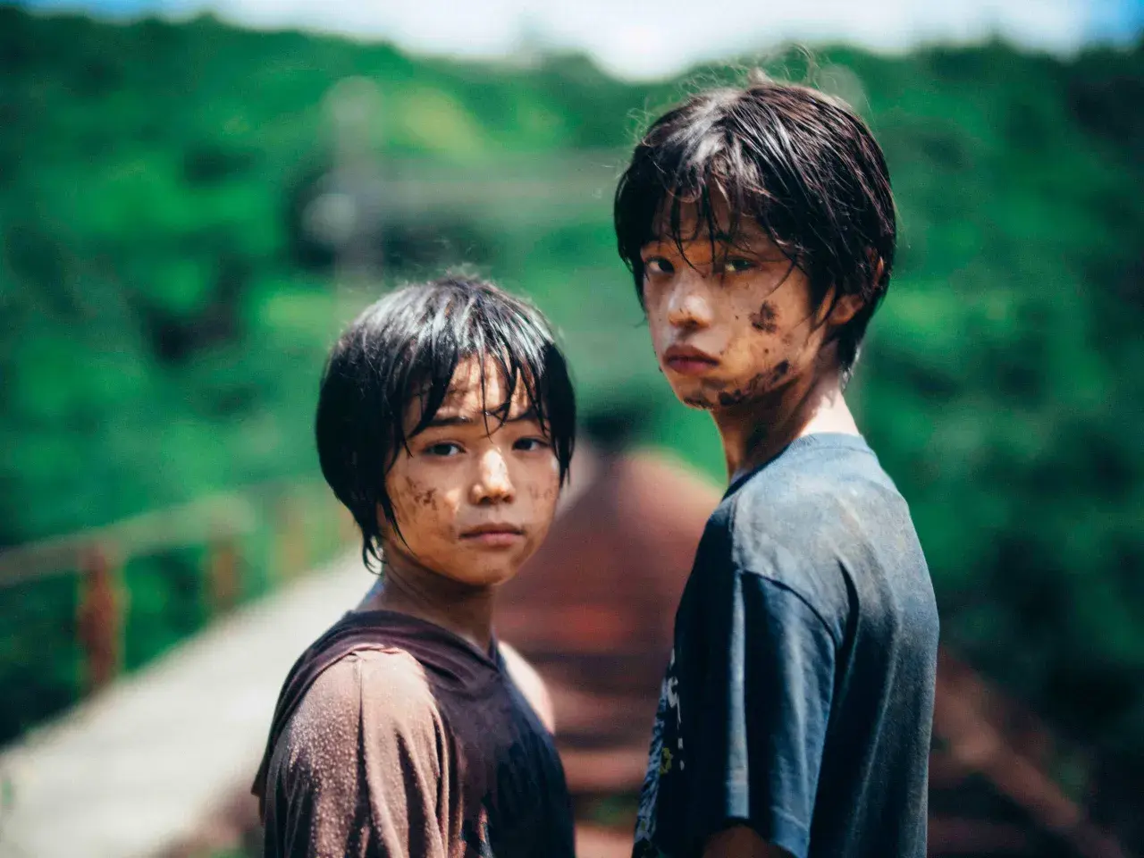 Due ragazzini sporchi di terra, con sguardi intensi, sembrano usciti da un film di mostri. Le loro espressioni suggeriscono storie che meritano recensioni.