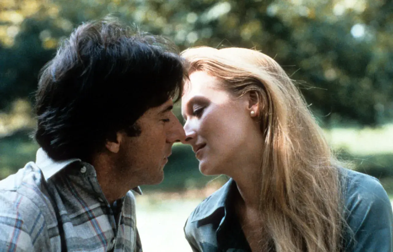 Un tenero momento tra John Cazale e Meryl Streep, i loro volti vicini in un abbraccio intimo.