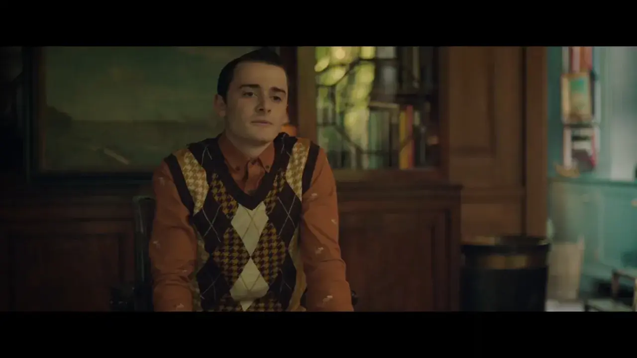 Il cast di The Tutor in un'ambientazione classica. Un giovane con un gilet a rombi su una camicia arancione.