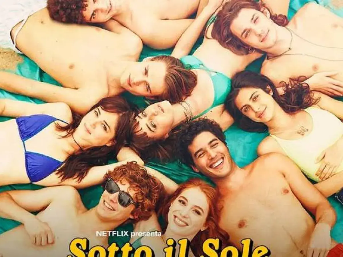 Giovani sorridenti sdraiati al sole, un'immagine che evoca le vacanze estive e le recensioni positive di "Sotto il sole di Riccione".