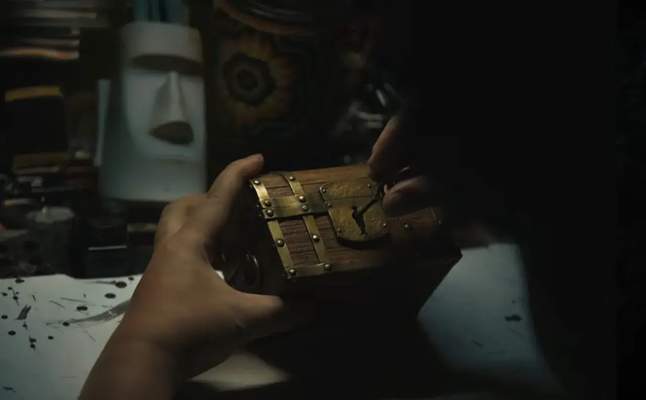 Mani che aprono un forziere, forse il tesoro di Gold Roger di One Piece. Sullo sfondo, una statua Moai e oggetti misteriosi.