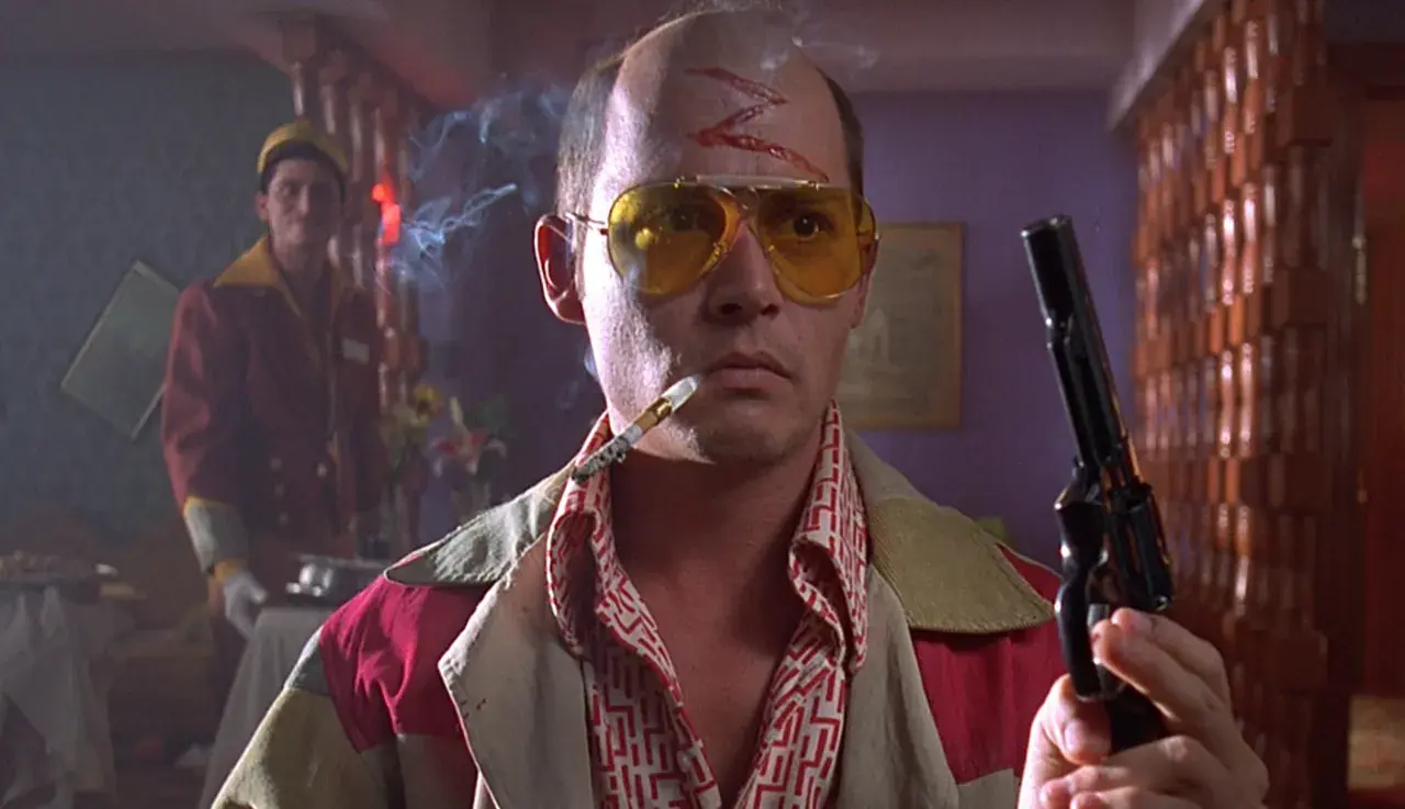 Un uomo con occhiali gialli, sigaretta e pistola, simbolo di paura e delirio a Las Vegas. Spiegazione visiva del caos.