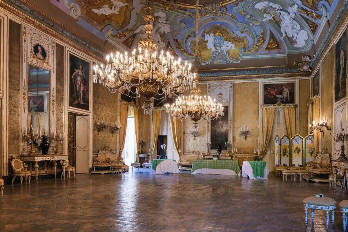 Salone sfarzoso con lampadari imponenti, arredi dorati e affreschi sul soffitto, pronto per il ballo del Gattopardo.