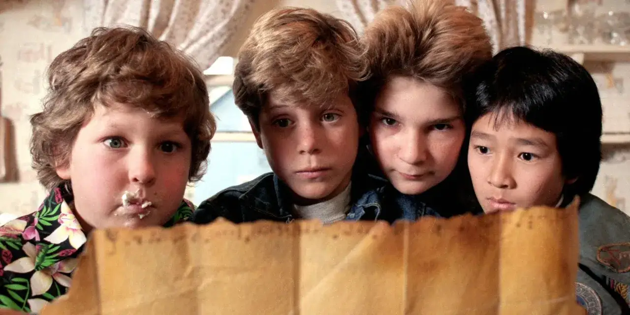 La banda dei fratelli Goonies studia una vecchia mappa, pronti per un'avventura.