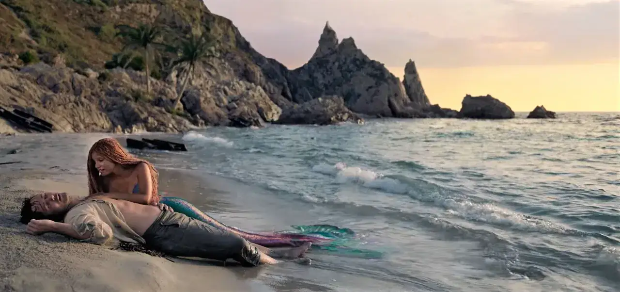 Una sirena con la coda colorata si china su un uomo naufrago sulla spiaggia. Travolti da un insolito destino, la curiosit&agrave; nei suoi occhi &egrave; palpabile.