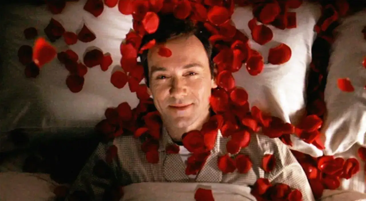 Un uomo giace su un letto coperto di petali di rosa, un'immagine iconica da