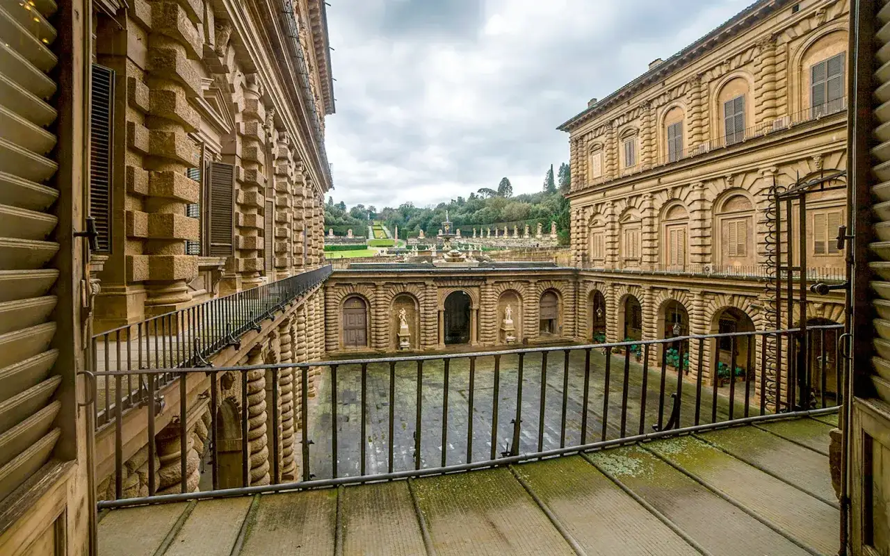 Cortile interno del Palazzo Pitti, con arcate, statue e un giardino all'italiana sullo sfondo.