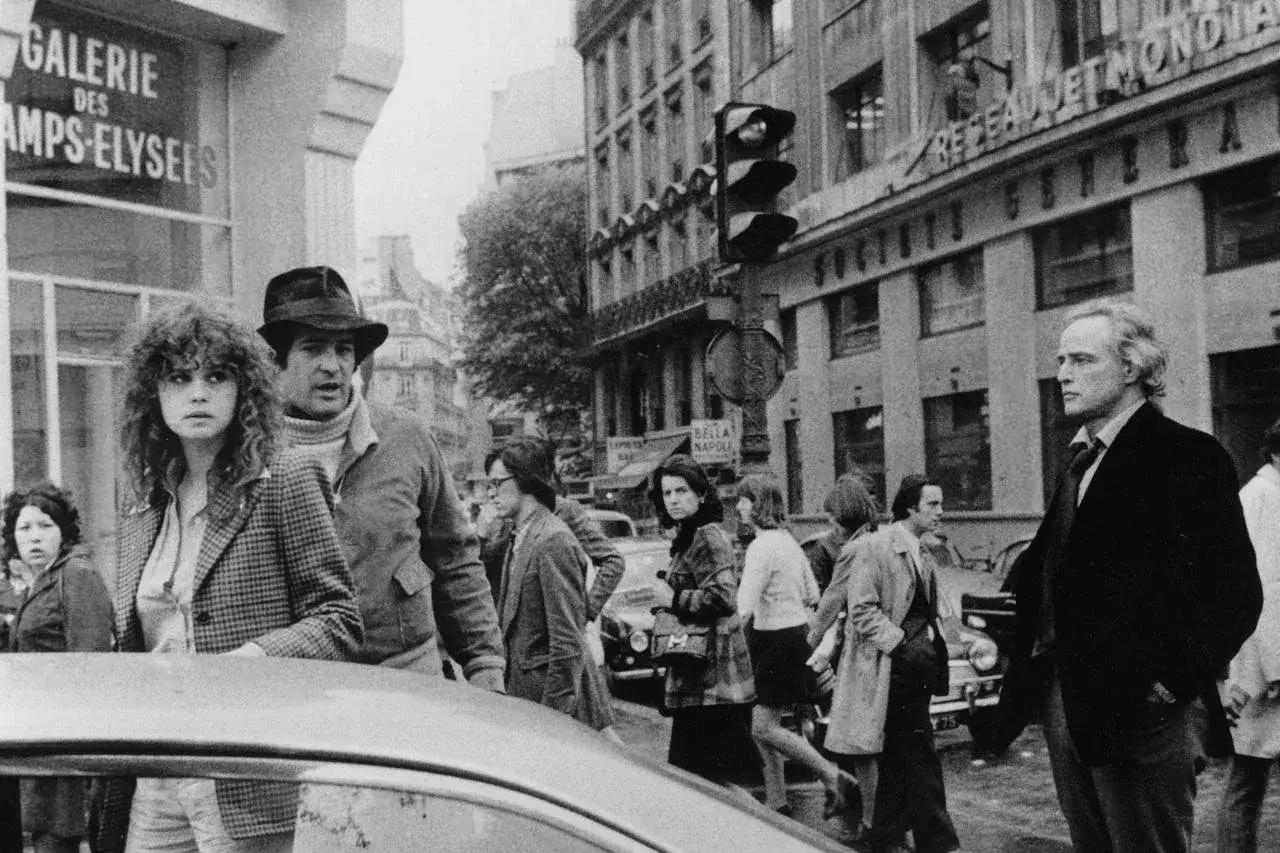 Ultimo tango a Parigi scena finale: Marlon Brando e Maria Schneider camminano per strada, circondati da passanti.