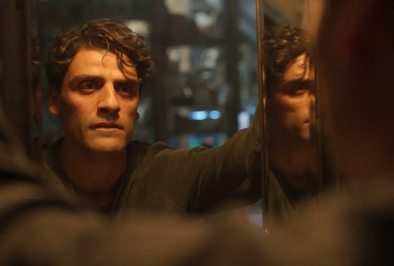 L'attore di Moon Knight, Oscar Isaac, si guarda riflesso in uno specchio, con uno sguardo intenso e pensieroso.