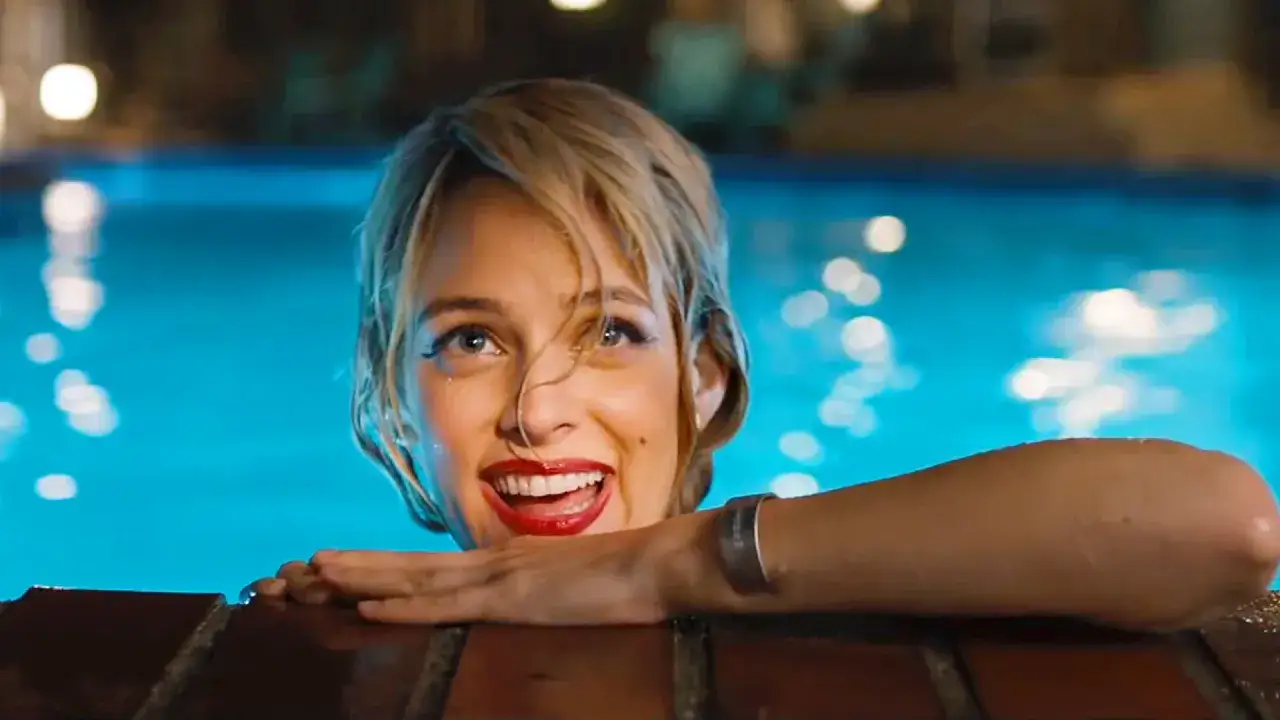 Una donna sorride dall'acqua di una piscina, con un bracciale d'argento al polso. Una scena che ricorda 