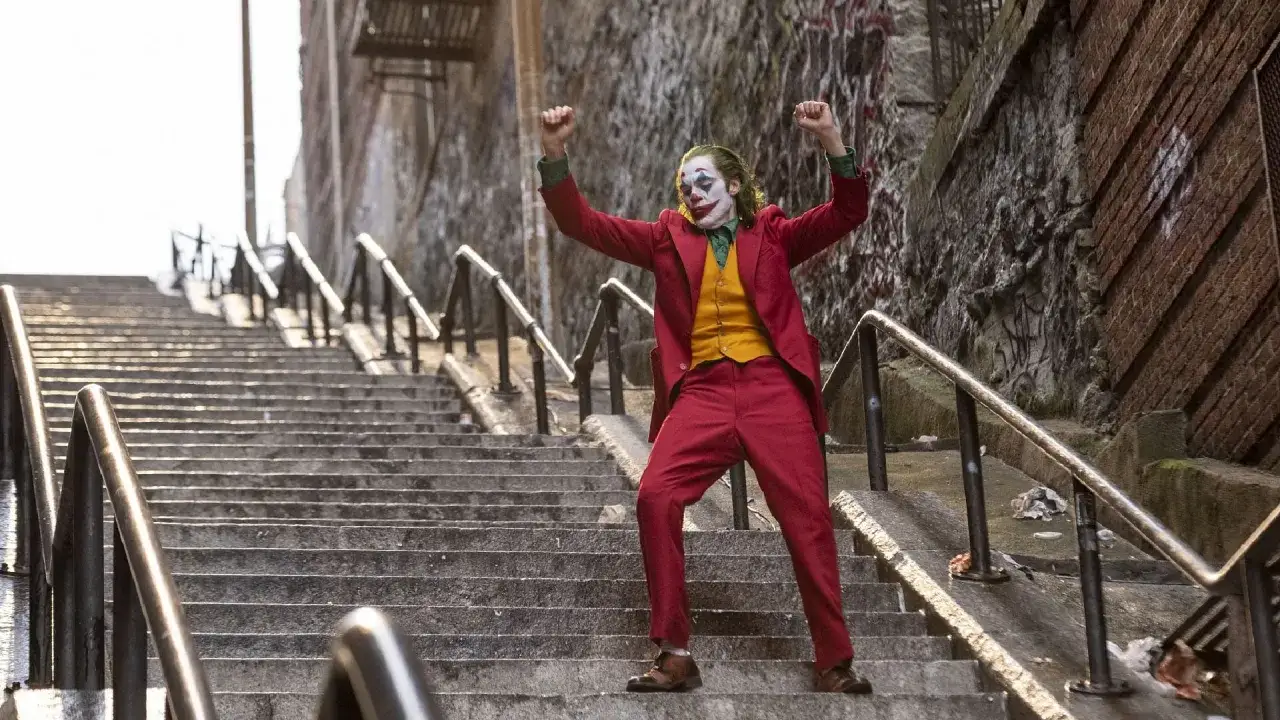 Joker, con trucco e abito rosso, danza sulle scale, un'icona del caos e del significato profondo del personaggio.