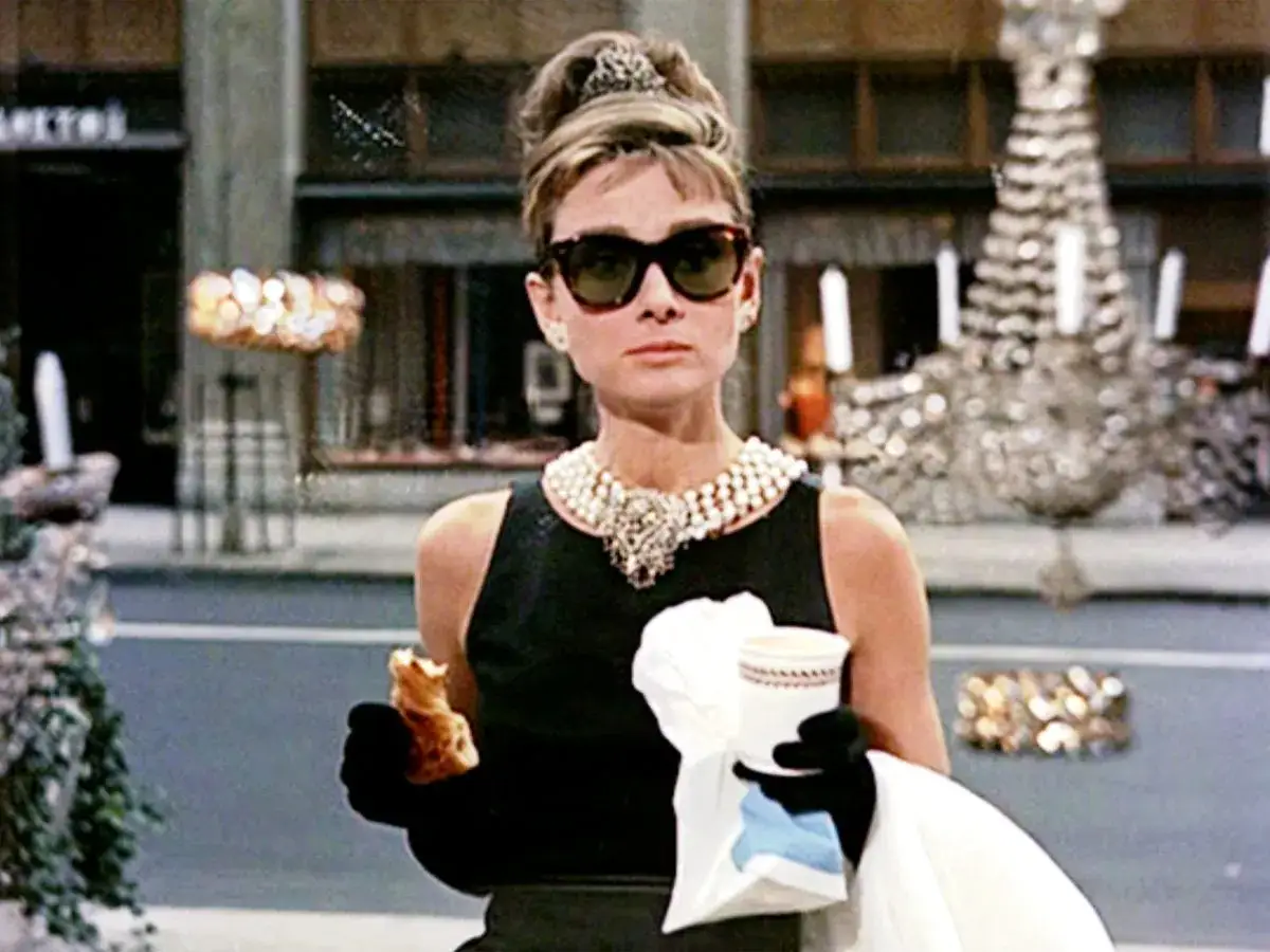 Audrey Hepburn, icona di stile, gusta una brioche davanti a Tiffany's. Un'immagine che evoca la magia di 