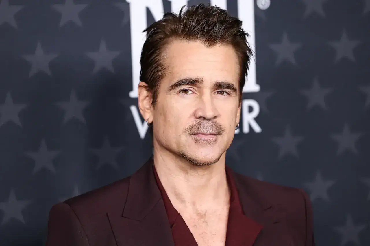 Colin Farrell, protagonista di tanti film, posa con un completo bordeaux su sfondo di stelle.