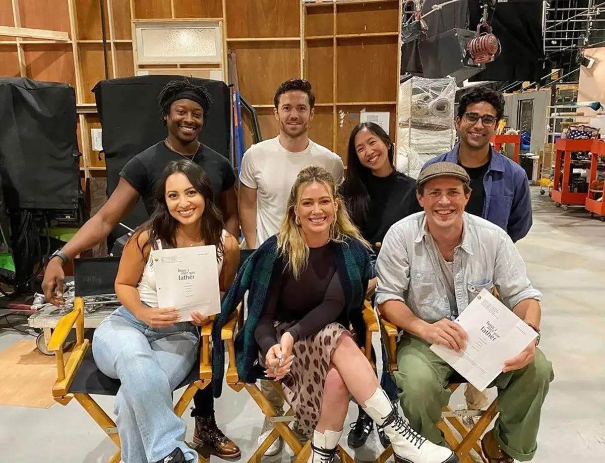 Il cast di How I Met Your Father posa sorridente sul set, tenendo in mano copioni.