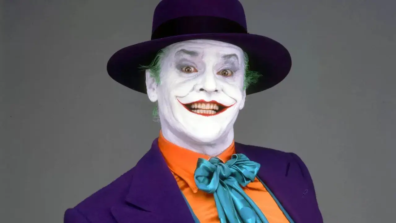 Jack Nicholson nel suo iconico ruolo di Joker nel primo film. Il suo trucco bianco, il sorriso inquietante e il cappello viola sono indimenticabili.